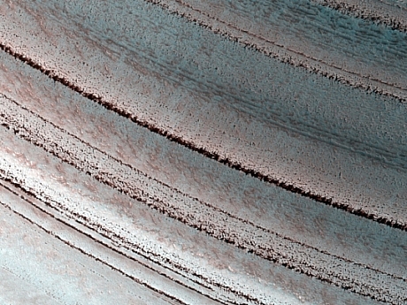 　この火星氷原の写真には、火星の気候変動を示す多くの地層が写っている。氷原の端の斜面では、これらの地層がむき出しになっている。NASAはこれらの地層をグリーンランドの氷原に見られる地層にたとえている。