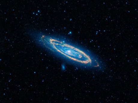 　この画像では、メシエ31（M31）とも呼ばれる有名なアンドロメダ銀河が、この上なく壮大に写っている。NASAのWISE望遠鏡は、4つの赤外線検出器のそれぞれを用い、このモザイク写真を撮影した。この写真の範囲は面積にして満月100個分以上、空全体のうち5度を占める。

　この画像の青い色は成熟した星を表し、黄色や赤は、新しい巨大な星に温められた塵を示している。

　アンドロメダは、銀河の中では最も地球に近く、250万光年しか離れていない。NASAによれば、「新しい星からなる環状の腕と古い星からなるぼんやりとした青い背骨」の詳細な様子は、望遠鏡で見ることができるという。この画像にはさらに2つの銀河が収められている。アンドロメダの中心の少し左上にあるM32と、渦状腕の中心の下にあるM10だ。この2つは、アンドロメダと重力によって結び付いている多数の銀河の中で最も大きい。

　NASAによれば、アンドロメダは天の川銀河よりも大きく、星の数も多いという。しかし天の川銀河は、暗黒物質と呼ばれるものが大量にあるため、質量では上回る可能性が高い。