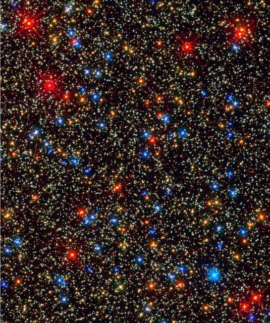 　NASAは、ケンタウルス座オメガ星団の一部に（相対的に）集中して分布している星が10万個存在すると述べている。黄色がかった白い点は、水素融合でエネルギーを得ている、いわば成人の星で、オレンジ色の点は晩年に差し掛かった星、ガスの外層を脱ぎ捨てつつある赤色巨星はさらに年配だ。