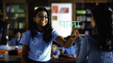 　この画像では、異なる国にいる2人の少女が、同時翻訳な透明ホワイトボードを使用して対話している。
