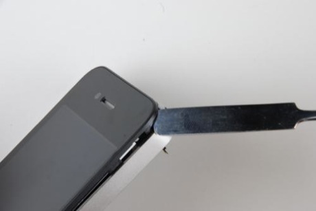 　金属の薄いへらを使って、iPhone 4のフロントパネルの周囲に沿って作業を進めてゆく。ガラスにひびを入れないように気をつける必要がある。