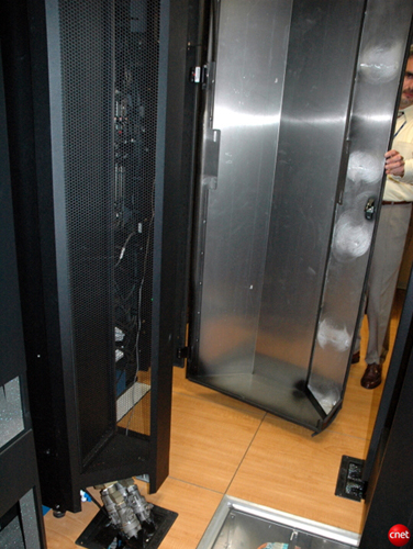 　このデータセンターでは、「Side Car」と呼ばれる、もう1つの冷却システムのプロトタイプもテストしている。Side Carは、ラックの背面に取り付ける代わりにラックの両側を囲う、循環する冷却水を使用した自己完結型冷却システムだ（左下に冷却水のパイプが見える）。IBMグリーン・イノベーション・データ・センターのプログラムディレクターで、開いたドアを押さえてくれているPeter Guasti氏によれば、このシステムを使用して、特定の「ホットスポット」を冷却することができるという。