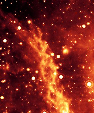 　写真の点は、赤外線星で、大半が赤色巨星と赤色超巨星だ。この領域にはそれ以外にも多くの星が存在するが、あまりにもぼやけているため、この高感度赤外線撮像でもよく見えない。この二重らせん星雲は、銀河系の中心にある巨大なブラックホールから約300光年の距離にある（地球は銀河系の中心にあるブラックホールから2万5000光年以上離れている）。この着色画像は、Spitzerのマルチバンド撮影フォトメーター（MIPS）によって撮影された。