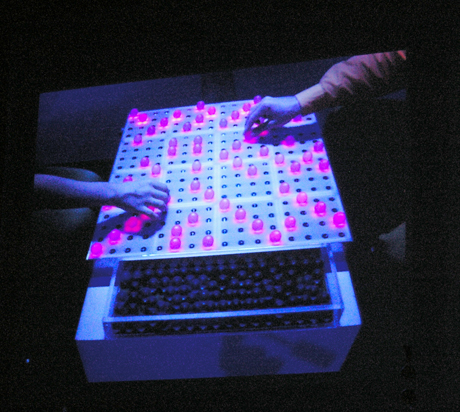 TENORI-ONの原型となった「音楽のチェス」は、岩井俊雄氏が1997年に考案した楽器。TENORI-ON同様にボタンがインターフェースとなっている。