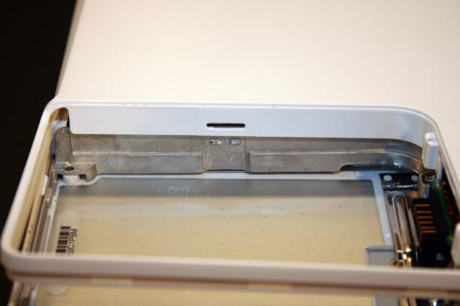 　底部のケーシングをiBookのシャーシから取り外すには、バッテリコンパートメント内にあるこのタブを含む複数のタブを押し下げる必要がある。
