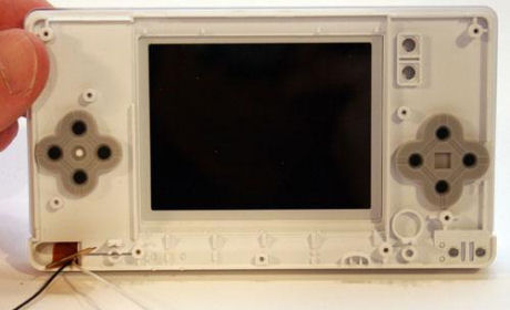 　DS Liteの下側のディスプレイを囲っているプラスチックケースの裏側の様子。右上に見える（中に円がある）2つの四角形は、STARTボタンとSELECTボタン。その下にある、野球のダイヤモンドの形をしたゴム引きパッドには、DS LiteのAボタン、Bボタン、Xボタン、Yボタンという操作ボタンが納まる。また、左側にも野球のダイヤモンドの形をしたゴム引きパッドがあるが、これは十字ボタン用だ。