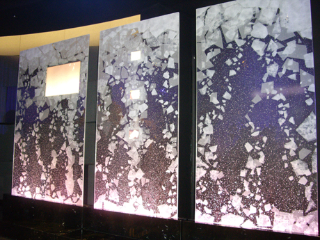 屏風のような存在感を持つ「遷（せん）」は、薄型テレビ用のスタンドとしてデザインされた。ミラノのガラス技術を駆使して作成されたスタンド部は、気泡やパターンがあしらわれ、エッジライトが盛り込まれるなど、幻想的な雰囲気を醸し出している。中央のパネルに3つの小型液晶が、左側のパネルには中型液晶が埋め込まれている。流されていた映像も雪の結晶や桜の花びらなど、四季折々のイメージ映像だった。