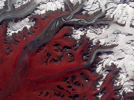 　これはアラスカのスシトナ氷河の写真で、下に流れていく氷生成をとらえている。NASAの衛星「Terra」に搭載の高性能熱放射反射放射計（ASTER）で、2009年8月27日に撮影された。赤、緑、赤外線の波長から、実際とは異なる色が作り出されている。ここでは、草木は赤色で、氷河の表面は汚れのない青色の氷と汚れのある茶色の氷で表されている。