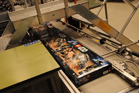 　内容物がそろい、ふたを閉じたLEGO Star Warsセットの箱が、包装ラインから出てくる。
