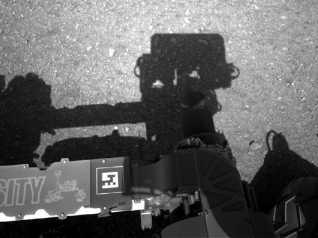 　これは、Curiosityが長旅を経て火星で目覚めたときにナビゲーションカメラで撮影された最初の画像だ。現在は直立している同探査機のマストがここでは真ん中に写っており、アームの影が左側に見える。アーム自体は前景に写っている。

　マストに搭載されたこのナビゲーションカメラは、太陽を探すのに使われる。太陽は地球の位置を確認し、地球と通信するために必要な情報だ。カメラは太陽の方を向いた後、正反対の方向に回転して自らの影を観測することで、太陽の位置を確認するとともに、それによって探査機自体の位置も確認する。

　1024×1024ピクセルのフル解像度画像はこちらで見ることができる
