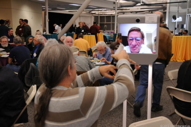  Homebrew Computer ClubのMarty Spergel氏がメンバーの再結集イベントでテレプレゼンスロボットを介して他のクラブメンバーにあいさつをしている。