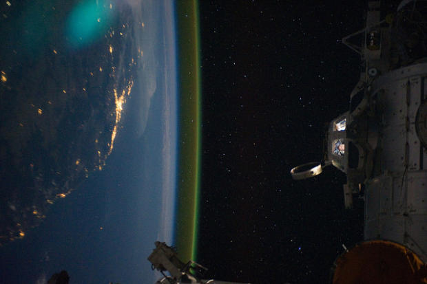 　国際宇宙ステーションのキューポラのはるか下方に、オーストラリアのブリスベンが見えている。一方キューポラ内部では、クルーが活動している様子が見える。