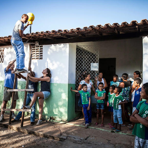 ブラジルのカンポマイオルで生徒たちが見守るなかLoon用インターネットアンテナを取り付けるProject Loonチーム