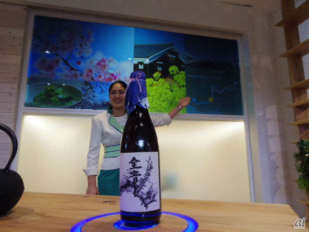 　井戸端コミュニティにおかれたテーブルでは、日本酒をブルーの円の中に置くと、コミュニティサイネージに日本酒の情報が表示された。いろいろな人が集まるスペースだからこそ、こうした情報表示が会話のきっかけにもなる。