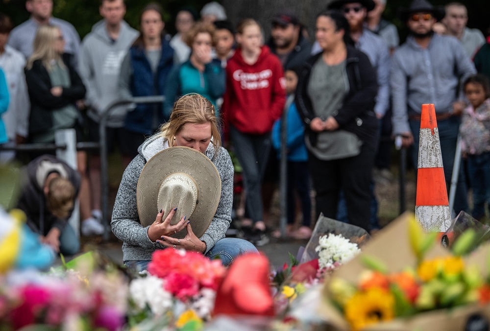 ニュージーランドのクライストチャーチで3月に起きた銃乱射事件後、現場になったアルヌールモスクに花を供え、帽子で顔を覆う女性