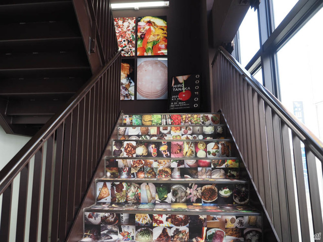 　さまざまな料理の写真が並ぶ壁と階段。