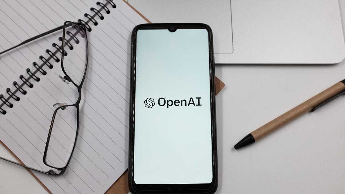 OpenAIのロゴが表示されたスマートフォンと、ノートやメガネ