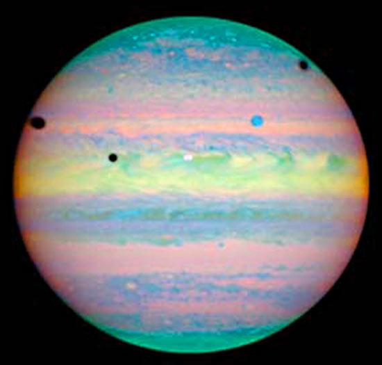 　地球では日食は珍しいことだが、この写真には、木星で同時に3つの日食が起こっている様子が写されている。Hubble望遠鏡によるこの画像では、木星の確認されている16の衛星のうち、3つが落とした影が黒い点となって見える。左から順に、ガニメデの影、イオの影、カリストの影だ。このうち2つは衛星自体もこの画像内に写っている。衛星イオは惑星の中心近くに写っている白い丸で、ガニメデは中心から右上の方にある青い丸だ。カリストは写っていない。