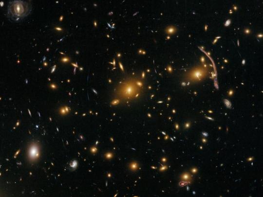 　銀河団エイベル370の光の弧や線が、「重力レンズ効果」を示している。これは、背後にある遠くの銀河からの光線が銀河団の重力場によって屈折する現象だ。このレンズ効果を利用して、銀河団における暗黒物質の分布状況が測定される。
