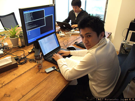 　CTOの秋田真宏氏。デュアルディスプレイを前に技術書を見ながらプログラムコードを書いていた。