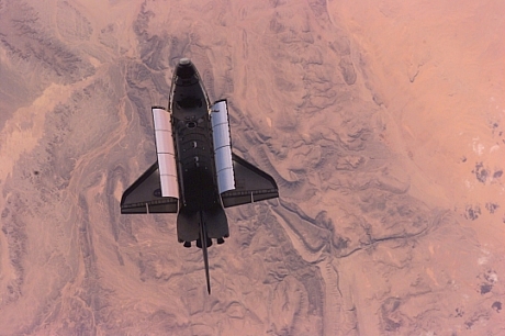 　2002年2月、国際宇宙ステーションを出発した直後のスペースシャトルAtlantisの写真。下には地球の砂漠が見える。