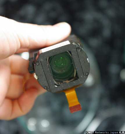 　レンズ部はコニカミノルタ製の超薄型レンズを採用。幅は約15mmの超薄型レンズだ。8群11枚から構成され、デジカメレンズ同様の周辺光量／解像度とビデオカメラに求められる追従性を実現しているとのこと。