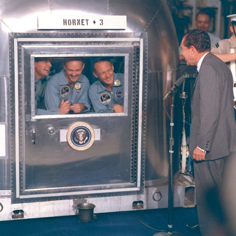 　帰還した宇宙飛行士にあいさつするためにU.S.S. Hornetに乗船したRichard Nixon大統領。Apollo 11号の3名は、移動式隔離設備の中で過ごした後、ヒューストンの有人宇宙飛行センターにある月資料研究所に移った。
