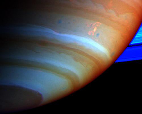 　2004年9月中旬に土星の南半球に現れた、巨大で明るく複雑な対流嵐は、リングがあるこの惑星についての長年の謎を解く鍵だった。

　この画像では、土星の大気とそのリングが、疑似色合成画像で示されている。これは、さまざまな量のメタンガスを検知するフィルタを使って、近赤外線で撮影したCassiniの画像から作成されたものだ。雲の上にメタンガスが大量に存在する場合、その部分の大気は赤色で示されており、大気中で高度が低いところに雲が存在することを示している。灰色は高い高度にある雲を示しており、茶色は中間的な高度の雲を示している。リングの粒子とカメラの間にはメタンガスが存在しないため、リングは明るい青色になっている。

　中心から少し右上にある、腕のような形と二次的な延長部分を持つ複雑な構造は、ドラゴンストームと呼ばれている。ドラゴンストームは、南半球の1地域に位置しており、2007年にCassiniで活発な嵐の活動が観測されたことから、イメージング研究者たちはこの地域を「嵐の通路」と呼んでいる。

　Cassini-Huygensミッションに関する詳しい情報は、http://saturn.jpl.nasa.govにある。画像は、Cassiniイメージングチームのホームページhttp://ciclops.orgで見ることができる。