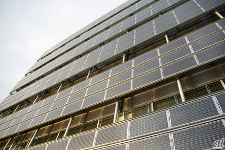 　管理棟と呼ばれるビルの壁面にも太陽光発電システムが設置されている。ここに利用されているのは両面発電型の太陽電池「HITダブル」。裏面を空調の余剰空気で冷却することで、高温になる夏場でも高い変換効率を維持するとしている。