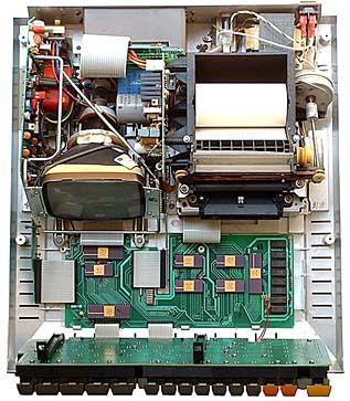 　トップを外すと、HP-85のすっきりとしてシンプルなレイアウトを見ることができる。左側にはモニタとディスプレイの回路、右側には感熱式プリンタとテープ記憶装置の機械部分がある。メインのマザーボードはキーボードの下にあり、この写真では折りたたまれている。8つのメモリチップ以外、チップはすべてHPが設計したカスタムだ。