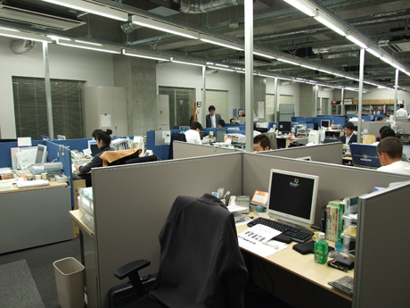 廊下からオフィスに入ったところ。コミュニケーションしやすく、かつ社員同士の目線が極端に合わないように4つ単位で配置された机。業務に集中できるよう配慮されたレイアウトとなっている。現在の社員数は46名、このオフィスには2007年11月に移転してきた。