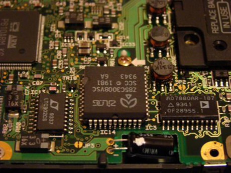 　逆さまになっているこのチップは、Zilogの型番Z85C3008VSCのCMOS版シリアルコントローラ。Newtonのシリアルポートを制御するチップで、これによりNewtonをPCに接続することが可能になる。大半のシリアルコントローラがRS232であるのに対し、ここではRS422標準チップとなっている。

　左側のLT902SCチップは、RS422チップのためのドライバ／レシーバチップ。右側のAD7880ARチップは、アナログからデジタルへの変換チップ。