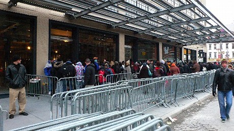 　ここはニューヨークの西14番街ミートパッキング地区。米国東部標準時間の12月6日は、凍てつくような寒さのうえに雪まで降り始めた。だが午後6時にオープンするApple Storeの前には、午後2時30分の時点で、数百人の長い行列ができていた。開店まで数時間あるというのに、約600人が並んでいたと見る人もいる。列の先頭の高校生は、なんと午前1時に並び始めた。これは間違いではない。午前3時半か4時までには、もっと多くの人々が行列に加わり始めたと、彼はCNET News.comに対して話している。しかしながら、本格的に行列ができ始めたのは、午後の早い時間帯だ。この地域の一部の学校は金曜日に早目に終わるため、学生たちにとっては、金曜日の午後から週末を迎えることになる。さらに大人のAppleファンは、凍てつく寒さの中で並ぶため、仕事を早く切り上げた。