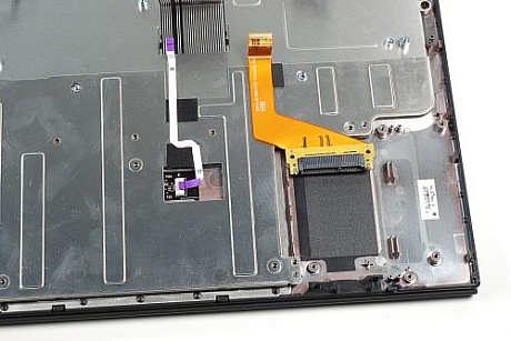 　SSDリボンケーブルは金属フレームに接着剤で固定されているため、SSDコネクタをプラスチックケースに固定している2本のプラスねじも取り外す必要がある。