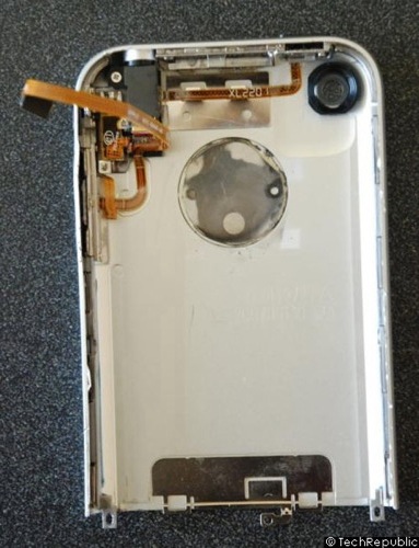 　iPhoneの電源ボタン、ボリュームボタン、バイブレータのスイッチ、ヘッドフォンジャックは、すべてバックパネル上に配置されている。バックパネルには、カメラ用の穴とアース用の金属板もある。大きな銀色の円は、パネルに埋め込まれたAppleのロゴマークの裏側だ。バックパネルの上部右隅にある小さな黒い円は、カメラ用の穴。電源ボタン、ボリュームボタン、バイブレータのスイッチ、ヘッドフォンジャックは、すべて1本のリボンケーブルでメイン基板とつながっている。
