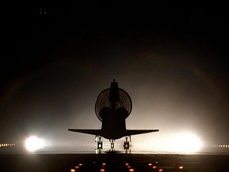　Discoveryが26回目の飛行であるミッションSTS-96を終え、ケネディ宇宙センターの明るく照らされたシャトル着陸施設で、ドラッグシュートを展開しているシルエットを見せている。