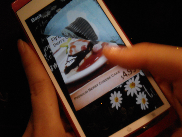 　カフェのメニューを使ったSmartARの紹介。スマートフォンでカフェのメニューを撮影すると、メニューがスマートフォン内に取り込まれ、手元でページをめくることができる。