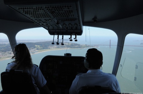 　飛行船Eurekaのパイロットらが、サンフランシスコ湾をゆっくりと越えていく途中で、窓からゴールデンゲートブリッジを見ている。