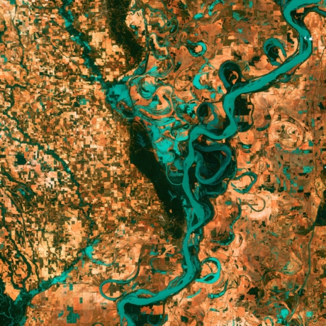 　2003年5月28日に撮影されたこの画像では、地球上に人類が居住している証拠である街、道路、農地、牧場が四角形で表されている。曲がりくねって渦を巻く青色で示される壮大なミシシッピ川とは対照的だ。