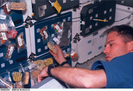 　スペースシャトル「Columbia」で、食料の整理をしている宇宙飛行士のRichard Searfoss氏。1998年4月18日に撮影。食べ物のパックは、面ファスナーを使ってトレイに取り付ける。