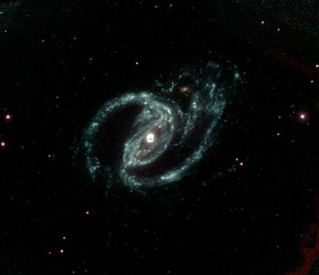 　「Arp 77」としても知られる「NGC 1097」は棒渦巻銀河で、その中心核は活発な大質量ブラックホールを内包している。

　地球から6100万光年の距離にあるろ座の「NGC 1097」は長い弧状の渦状腕を持っており、2時の位置に存在する輝度の低い伴星から部分的に影響を受けている。この伴星は、NGC 1097の明るい目のような中心点から約4万光年の距離にあり、Swiftの紫外フィルター（uvw1、uvm2、およびuvw2）を使って合成されたこの画像で何とか存在を確認することができる。

