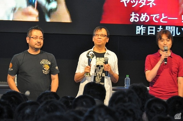 　スクウェア・エニックスブースでは、9月22日の「ドラゴンクエストX」バージョン2.0情報ステージにおいて、齊藤陽介プロデューサー（左）、齋藤力ディレクター（右）とともに、ゲームデザイナーの堀井雄二氏（中央）も登場。日本ゲーム大賞2013の年間作品部門優秀賞受賞を、手にしたトロフィーとともに報告。