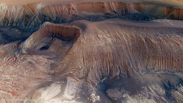 　欧州宇宙機関（ESA）初の惑星探査機「Mars Express」は、火星の写真撮影を開始してから10周年を迎えている。同探査機は、搭載された高解像度ステレオカメラ（High Resolution Stereo Camera：HRSC）で得たデータを使用して、ミッションの開始以来、数多くの画像を送り返してきた。

　HRSCは、約10mの空間分解能を持つカラー画像や3D画像として火星を撮影している。一部の特別な地域では、さらに詳細な2mの空間分解能での撮影を行った。このカメラの最大の強みの1つは指向精度の高さだ。空間分解能が異なる2種類の写真を組み合わせ、さらに、火星の地形をフルカラーで明らかにする地下探査レーダ高度計（Mars Advanced Radar for Subsurface and Ionospheric Sounding：MARSIS）によって得られた3D斜視図を用いることで、高い精度を実現している。

　HRSCの研究責任者であるドイツ、ベルリン自由大学のGerhard Neukum氏は、次のように述べている。「2mの空間分解能を持つ写真を、空間分解能10mの帯状の写真に組み込むことで、どこを観測しているのかを正確に知ることができる。2m分解能チャネルによって、地表の様子を非常に詳しく知ることができるだろう」

　これはMars Expressが撮影したヘベス谷内部のメサ（卓状台地）のクローズアップ写真だ。表面の物質が谷底に崩れ落ちており、丘の斜面に沿って、水平方向に細かな層が見える。おそらくこれは、風によって飛ばされたちりと古代の湖沼堆積物の混合物だろう。さらに、より古い時代の大地のなごりの地形も見える。