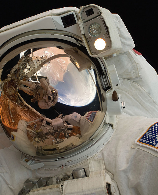 　John Grunsfeld宇宙飛行士を撮影したこのクローズアップ写真には、もう1人の宇宙飛行士であるAndrew Feustel宇宙飛行士がロボットアームの上に立って、この写真を撮影しているところが反射によって映り込んでいる。この写真は2009年に撮影された。