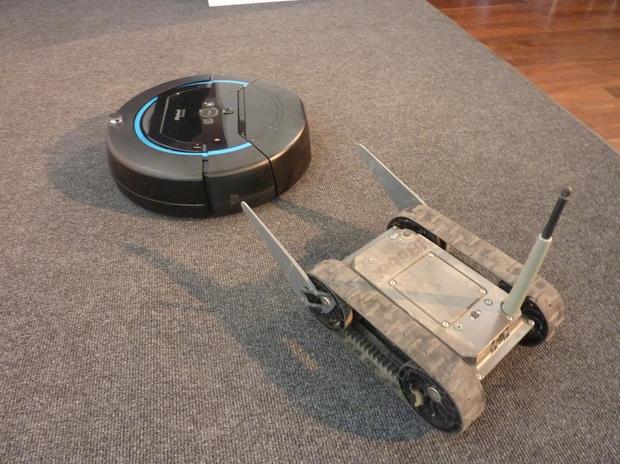 「FirstLook」、別名「Throwbot」

　まず、軍事目的用のモデルの1つとして「Throwbot」（投げられるロボット）という異名を持つ「FirstLook」がある。投げられるロボットという名で呼ばれる理由は、この監視ロボットが軽く作られており、窓から屋内に投げ込んだり、屋根の上に投げ上げたりして使用できるためだ。写真は、FirstLookがiRobotの開発した兄弟分に当たる家庭用床掃除ロボット「Scooba」を調査しているところ。