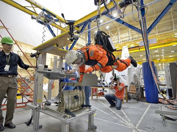 　進化したOrionの乗員用モジュールは、最終的に乗員が搭乗すると、新しい宇宙服と連携して機能するようになっている。この宇宙服「Advanced Crew Escape Suit（ACES）」は、Orionの生命維持システムと完全に一体化するようになっている。これは、スーツの着用者を宙吊りにして微小重力環境を再現する装置で、ACESをテストしているところ。