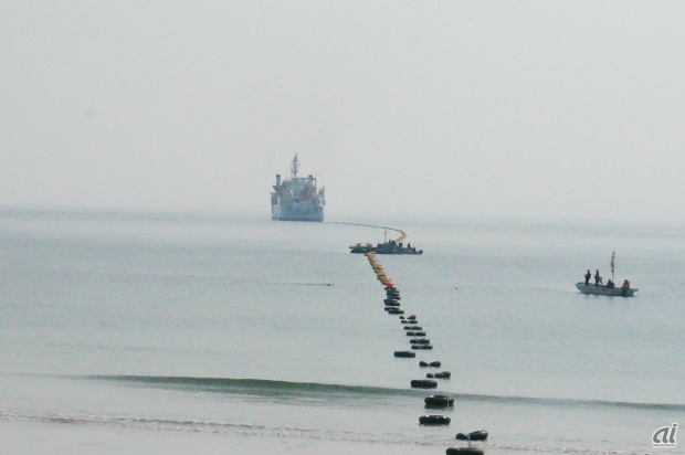 　三重県志摩市にあるKDDI南志摩海底線中継所付近の海岸にケーブル敷設船がやってきた。沖合約1.4kmから陸揚げ用のロープを繰り出し、陸揚げを開始する。