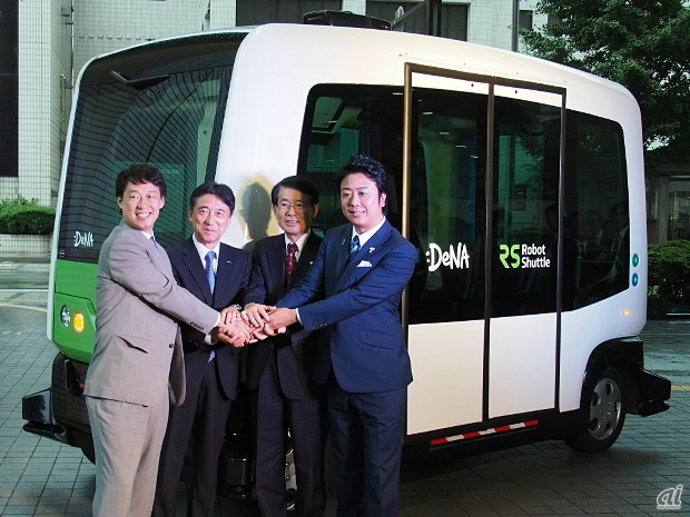 実証実験に用いる自動運転バス「EZ10」の前で握手を交わす、コンソーシアムに参加する各代表