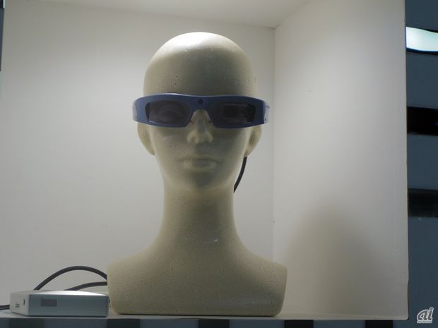 　富士通とQDレーザによる「網膜走査型レーザアイウェア」は、網膜に映像を映し出せる視覚支援ツール。カメラが付いているため、その場の風景を映像として見ることもできる。