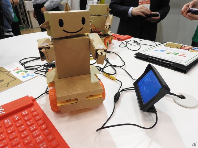 　小中学生向けのプログラミングロボット「ゾビーゴ」。段ボールから切り取ったパーツと、モーターや足を組み立てて、自分の好きなデザインのゾビーゴを作れる。プログラミングPC「IchigoJam」を使ってプログラミングし、自由自在に動かすことが可能だ。